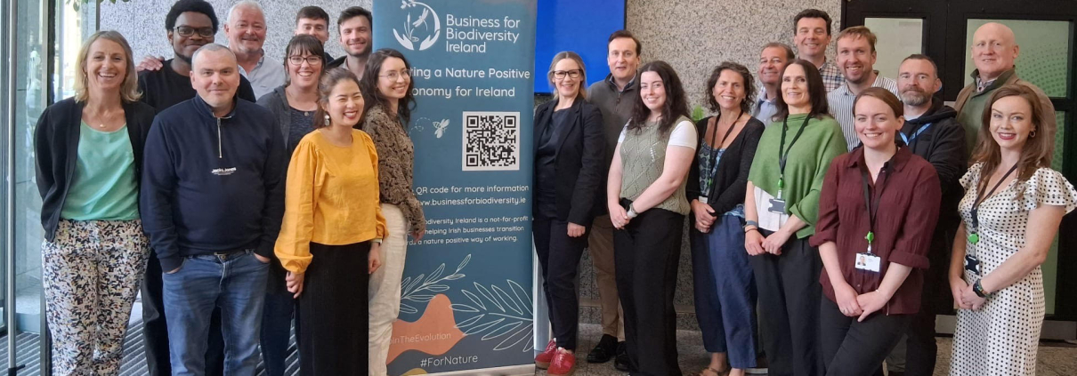 Group of people in lobby beside a teal poster with logo and QR code