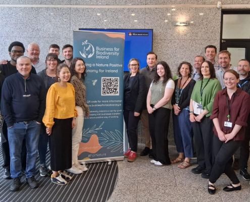 Group of people in lobby beside a teal poster with logo and QR code