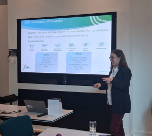 Woman speaks at large screenshowing text in blue boxes and small icons