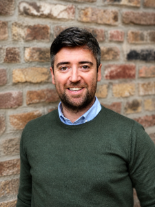 Headshot of smiling man with beard and green jumper